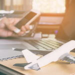 Close-up of a desk with a laptop, notebook, and airplane model, symbolizing efficient flight school management with a flight schedule program.