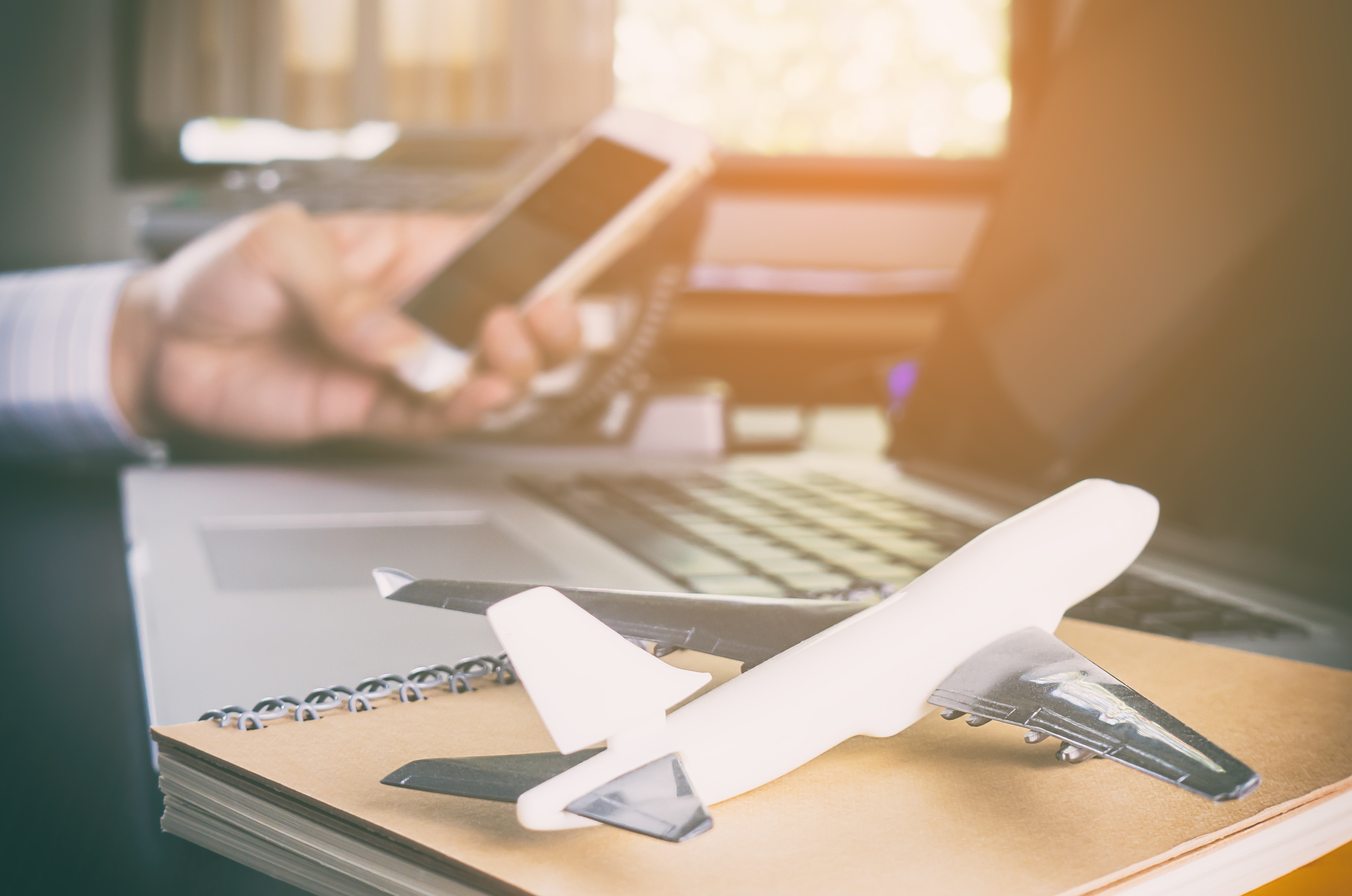 Close-up of a desk with a laptop, notebook, and airplane model, symbolizing efficient flight school management with a flight schedule program.