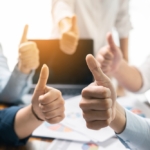 Team members giving a thumbs-up around a table, symbolizing collaboration and success with a well-optimized flight schedule using PreFlight for seamless scheduling and efficient operations.