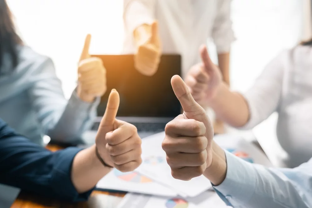 Team members giving a thumbs-up around a table, symbolizing collaboration and success with a well-optimized flight schedule using PreFlight for seamless scheduling and efficient operations.